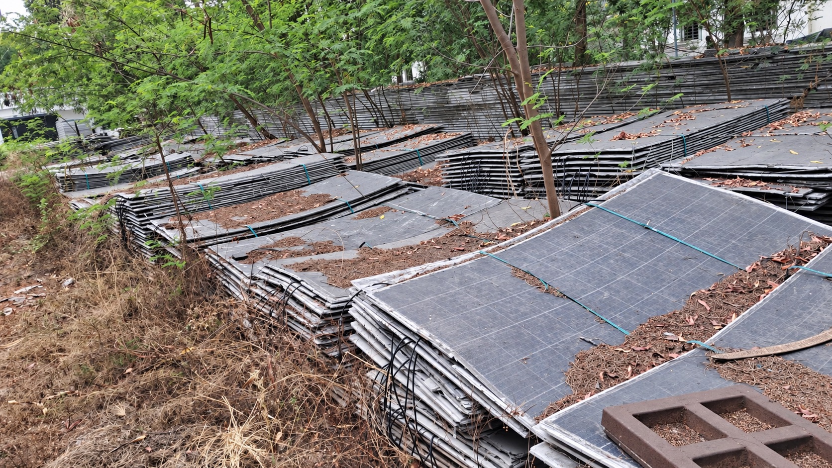 Weathered solar panels stacked outdoors in a previous enquiry