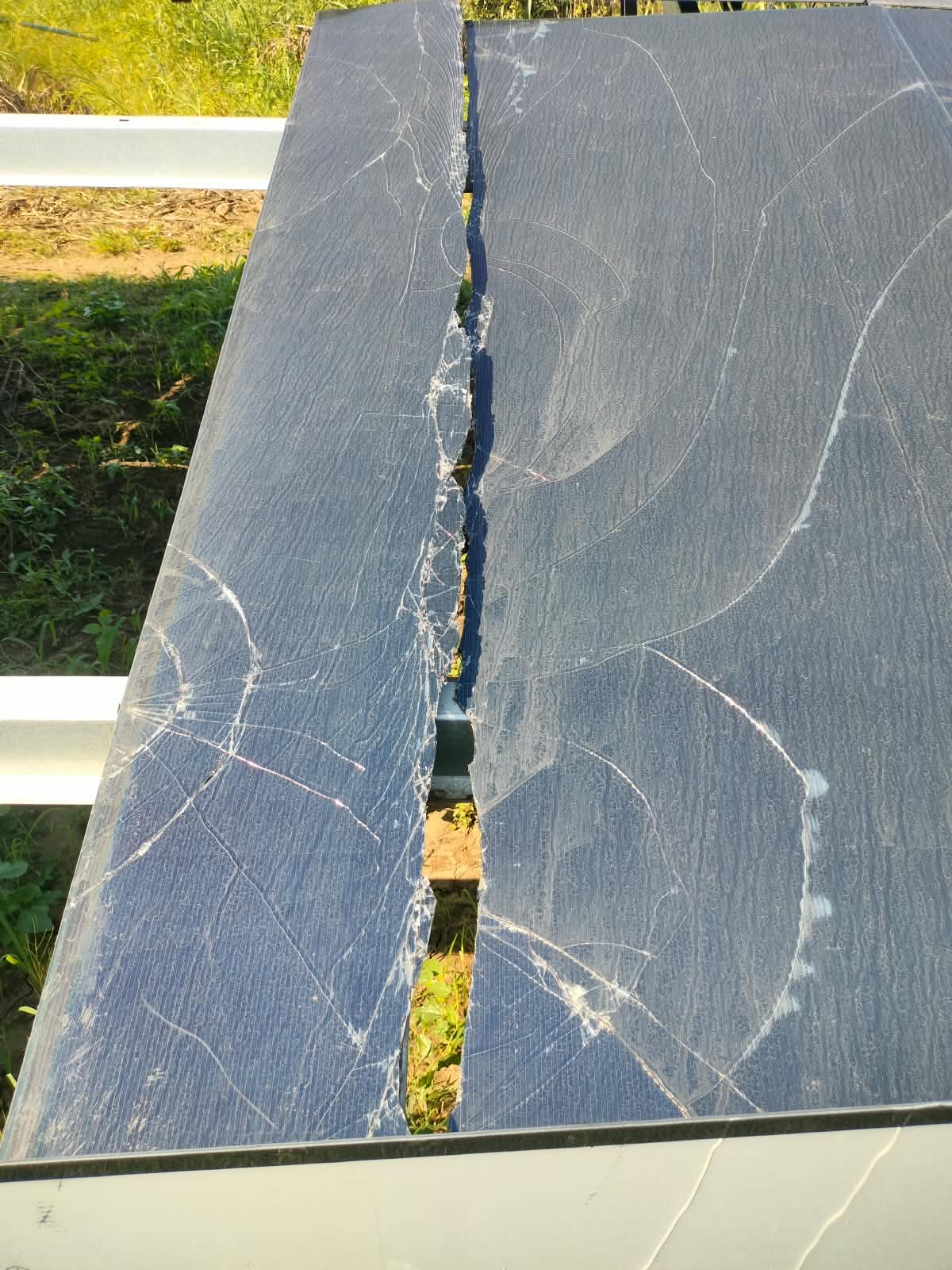 Solar panel with extensively cracked glass and a long broken section through its surface