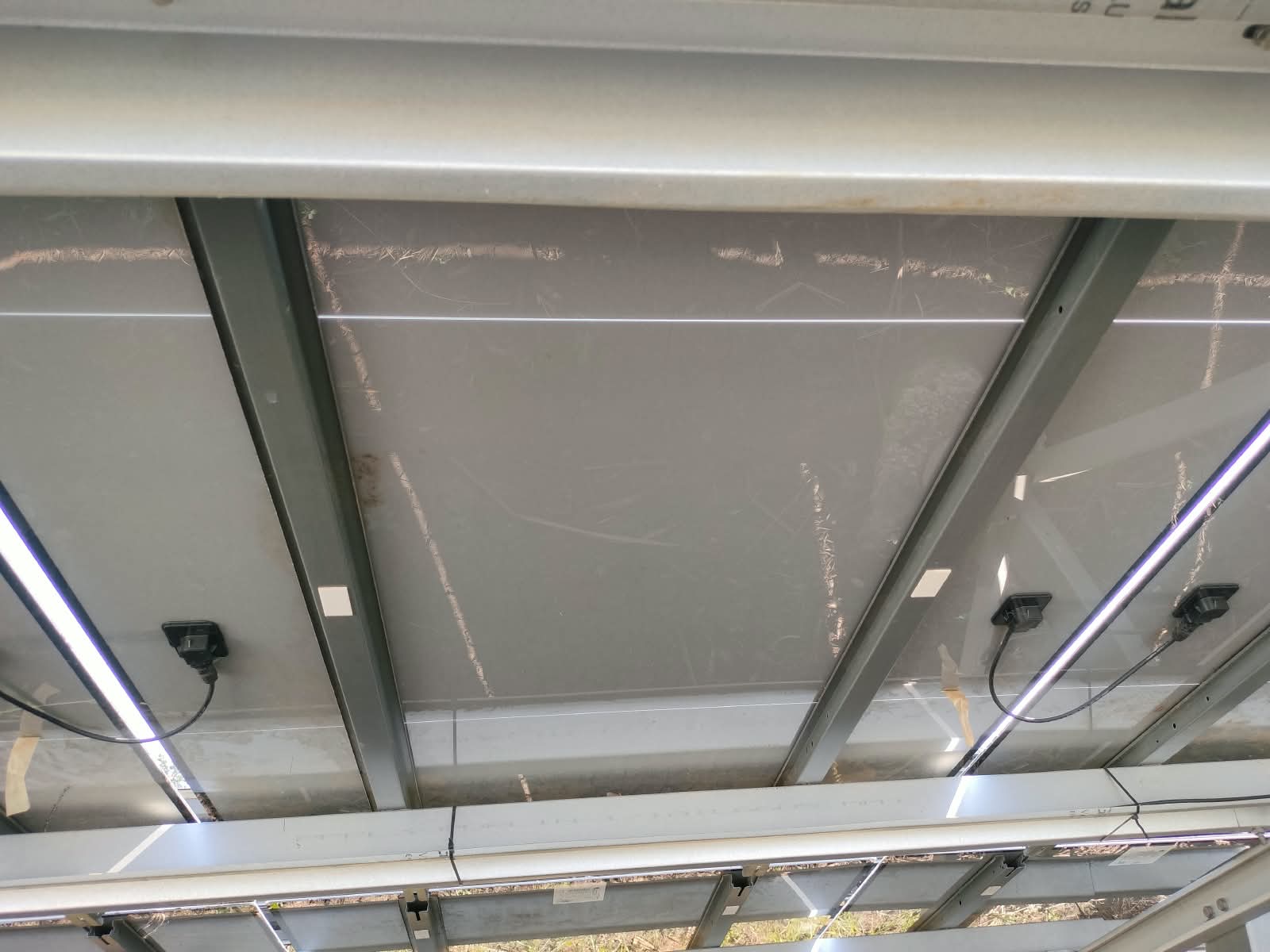 Undersides of solar panels showing rear surfaces, junction boxes, cables and metal support rails